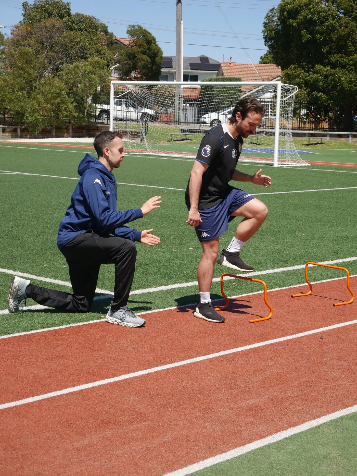 Jake coaching a footballer through mini-hurdle drills on the track