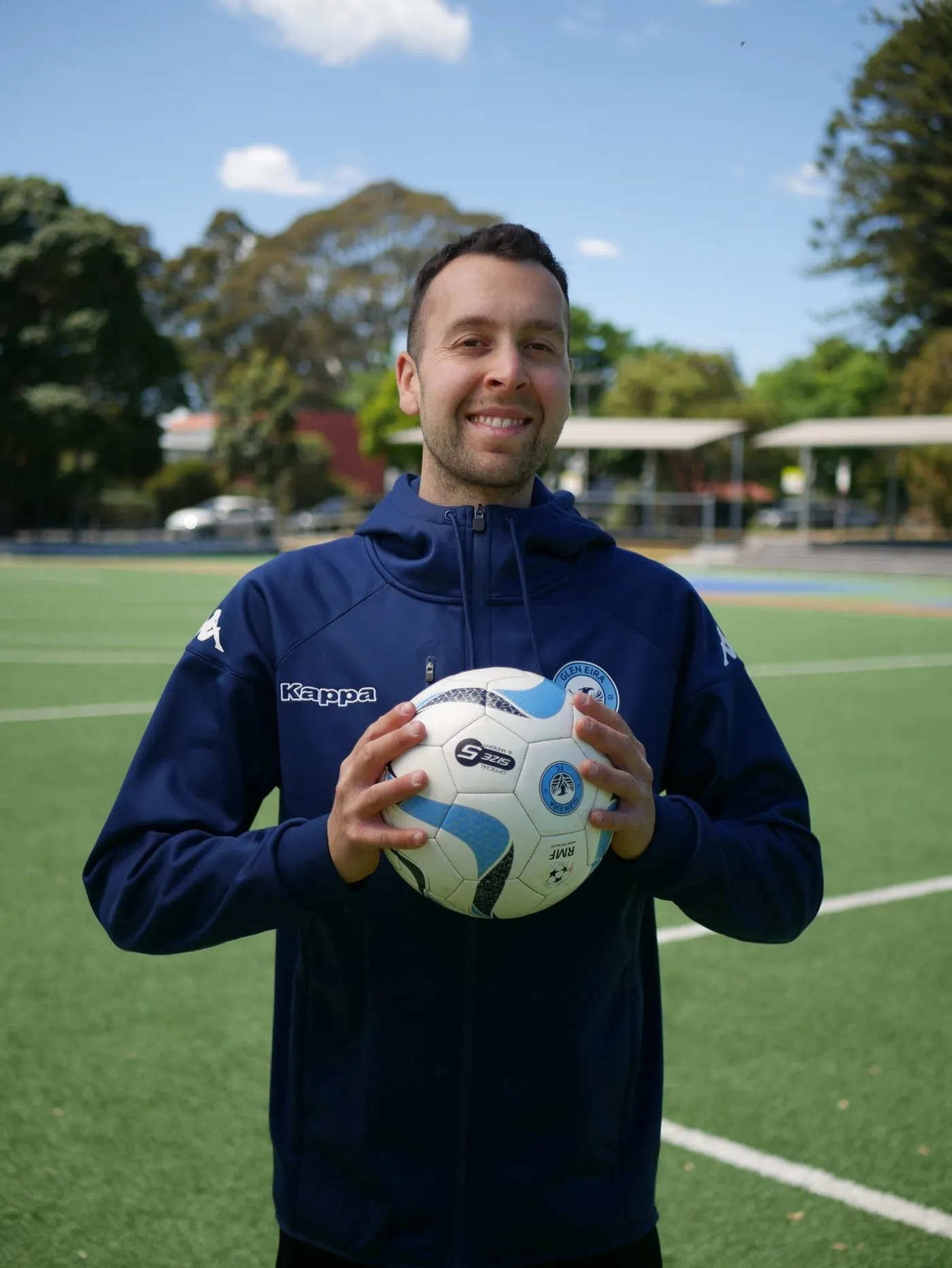 Jake Sugarman, physiotherapist and performance coach, holding a football on the pitch